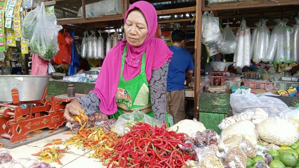 Nurminah, penjual bumbu dapur di pasar Pramuka Tuban sedang melayani pembeli (Foto: Khoirul Huda/Ngopibareng.id)