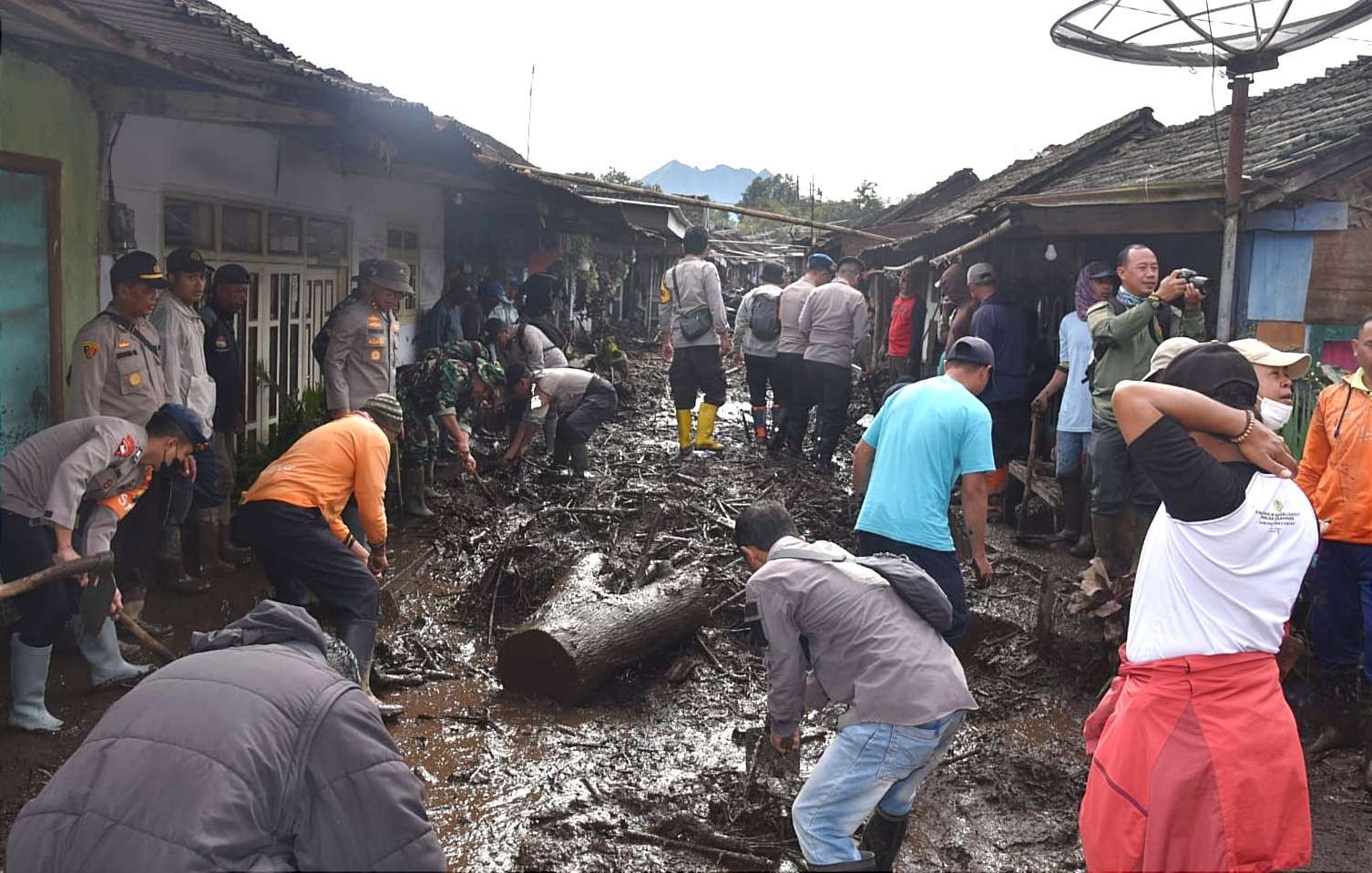 Anggota BPBD, TNI Kodim 0822,  Polres Bondowoso, relawan, dan warga gotong royong membersihkan material lumpur dan kayu banjir bandang Ijen Sempol, Senin 13 Februari 2023 pagi.(guido/ngopibareng.id)