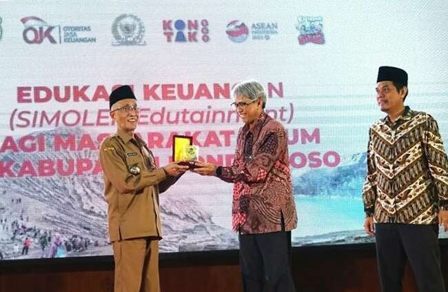 Kepala OJK Jember Hardi Rofiq Nasution (tengah) memberikan cindera mata kepada Bupati Bondowoso Salwa Arifin saat acara edukasi literasi jasa keuangan.(Foto:Guido/Ngopibareng.id)