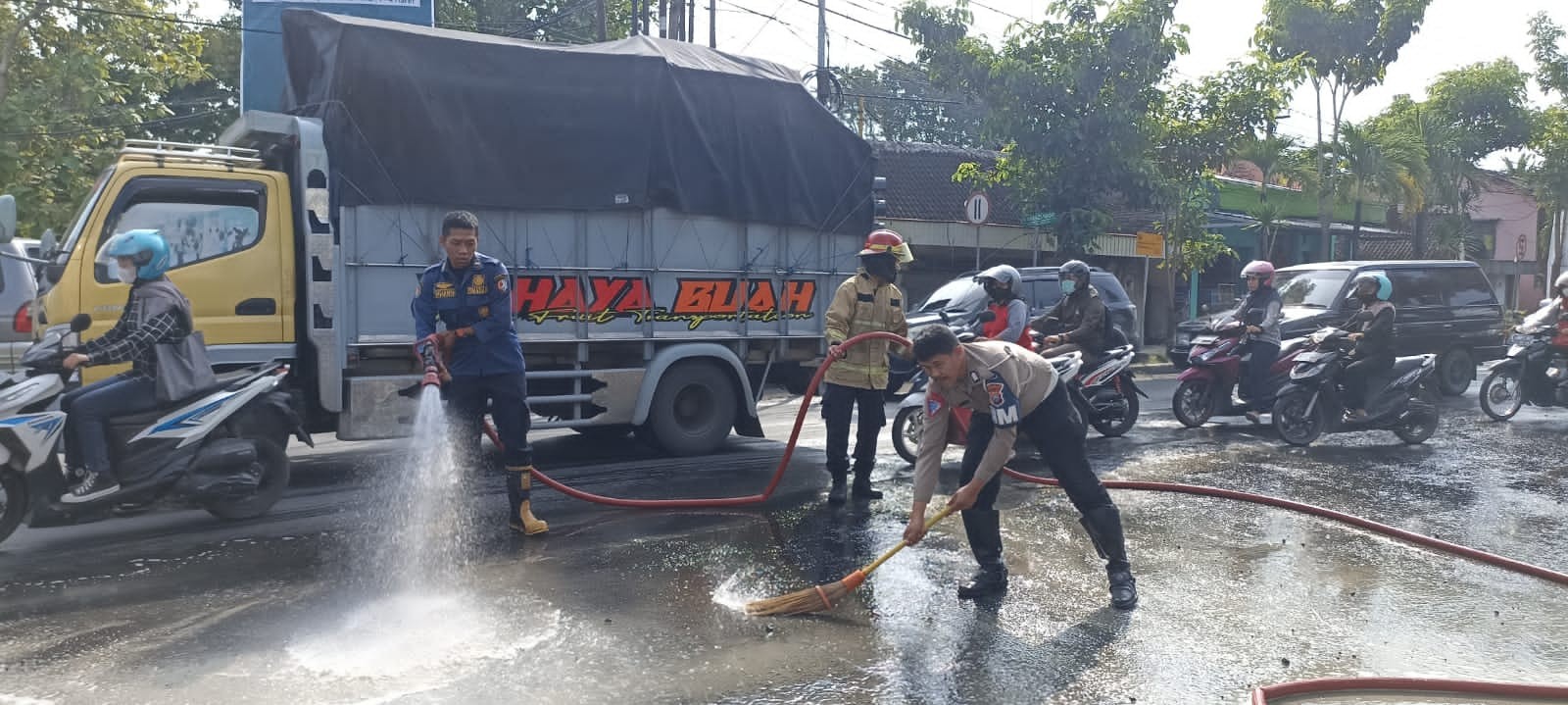 Anggota Satlantas Polres Bojonegoro dan petugas Pemadam Kebakaran (Damkar) gotong rotong membersihkan tumpahan material cor di depan Pos Jambean Kecamatan Kota Kabupaten Bojonegoro, Selasa 14 Maret 2023. (Foto: dok. Humas Polres Bojonegoro)