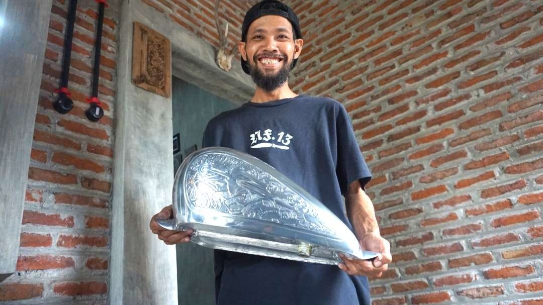 David menunjukkan hasil ukiran tangki. (Foto: Deni Lukmantara/Ngopibareng.id)