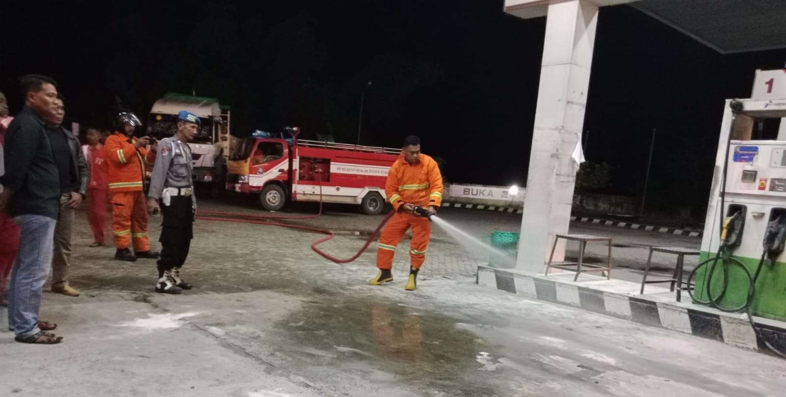 Petugas pemadam kebakaran (Damkar) melakukan pembasahan untuk memastikan api telah padam di SPBU. (Foto: Khoirul Huda/Ngopibareng.id)