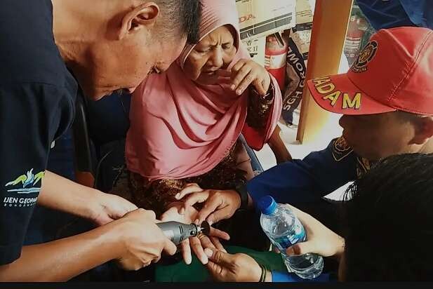 Seorang ibu meringis kesakitan saat anggota Damkar Bondowoso melepas tiga cincin dari jari tangannya.(foto:satpol pp-damkat Bondowoso)