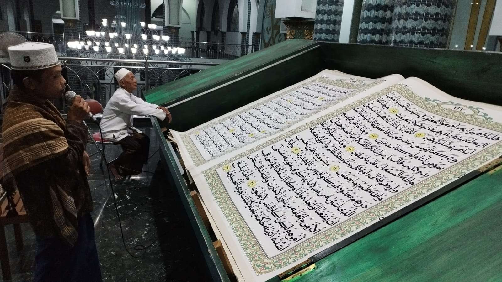 Salah seorang qori sedang melantunkan ayat suci Al Quran dengan Al Quran raksasa di Masjid Agung Baiturrahman, Banyuwangi (Foto: Muh Hujaini/Ngopibareng.id)