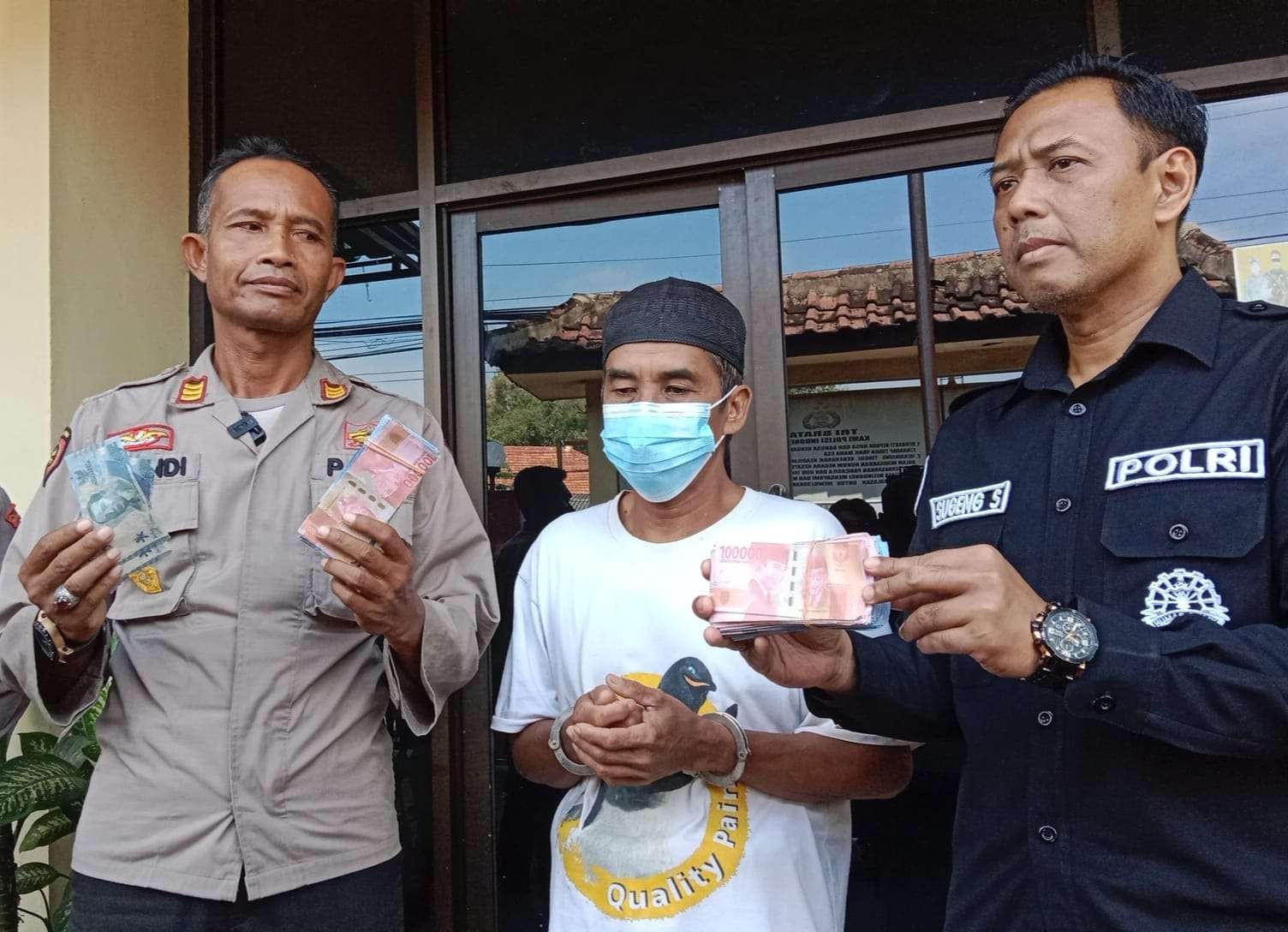 Tersangka pembuat dan pengedar uang palsu, Hanan, 56 tahun (tengah) bersama Kapolsek Besuk, AKP Achmad Gandi. (Foto: Ikhsan Mahmudi/Ngopibareng.id)