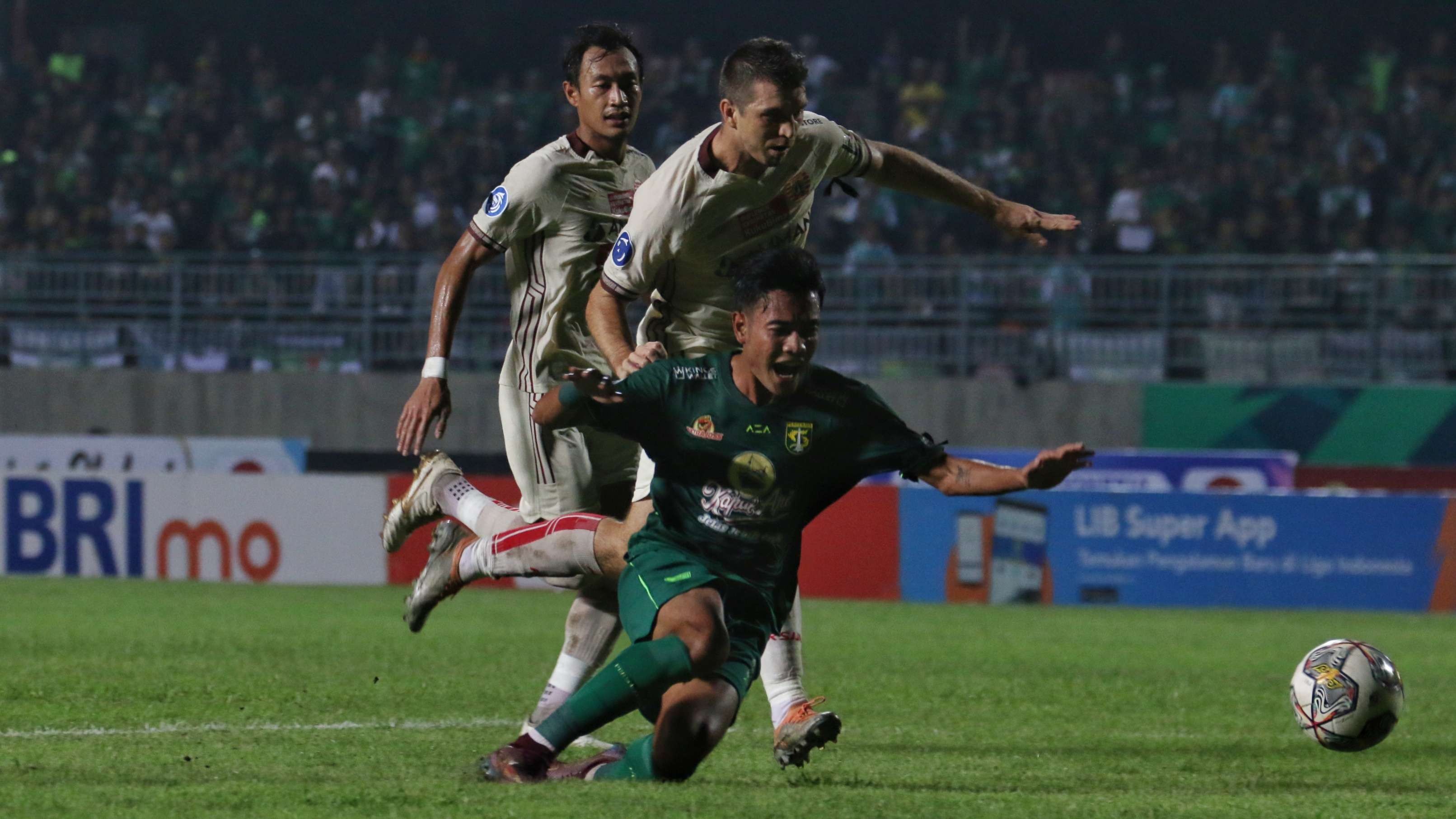 Pemain Persebaya, Brylian Aldama (hijau) jatuh usai dihadang pemain Persija Ondrej Kudela di Stadion Gelora Joko Samudro, Gresik, Rabu 5 April 2023. (Foto: Fariz Yarbo/Ngopibareng.id)