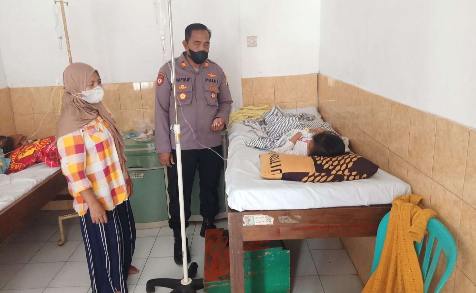 Kapolsek Ambulu, AKP Ma'ruf menjenguk korban keracunan massal. (Foto: Dokumentasi Polsek Ambulu)