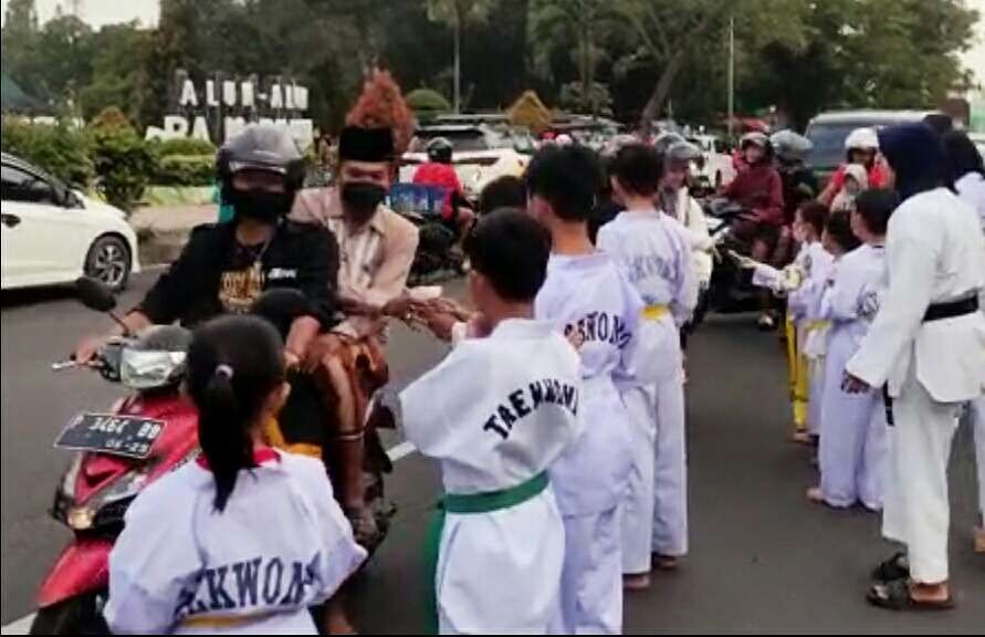 Pengendara motor menerima pembagian takjil jelang buka puasa dari para atlet taekwondo Bondowoso di kawasan jalan Alun-alun RBA Ki Ronggo Bondowoso.(Foto:Guido/Ngopibareng.id)