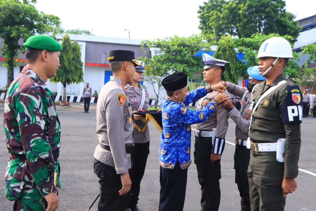 Sekda Tuban didampingi Kapolres dan Dandim 0811 Tuban menyematkan pita kepada perwakilan personel apel gelar pasukan operasi ketupat semeru 2023 (dok. Polres Tuban)