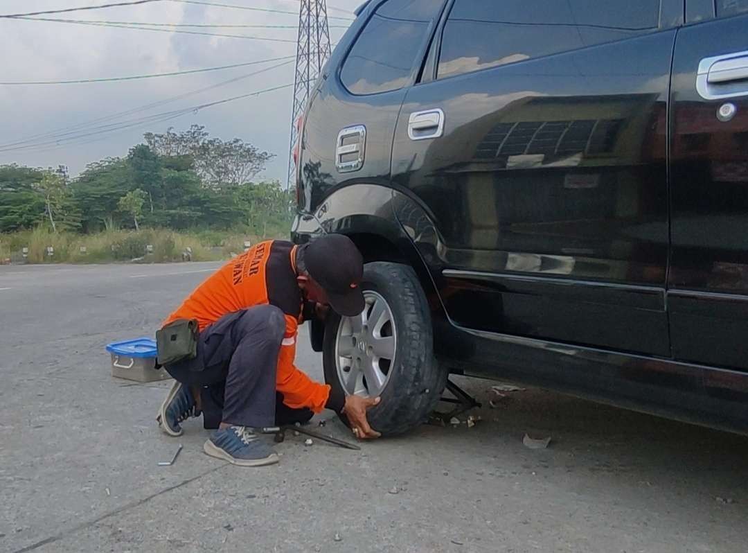 Odang melayani tambal ban mobil di Pos Pantau Semar. (Foto: Deni Lukmantara/Ngopibareng.id)