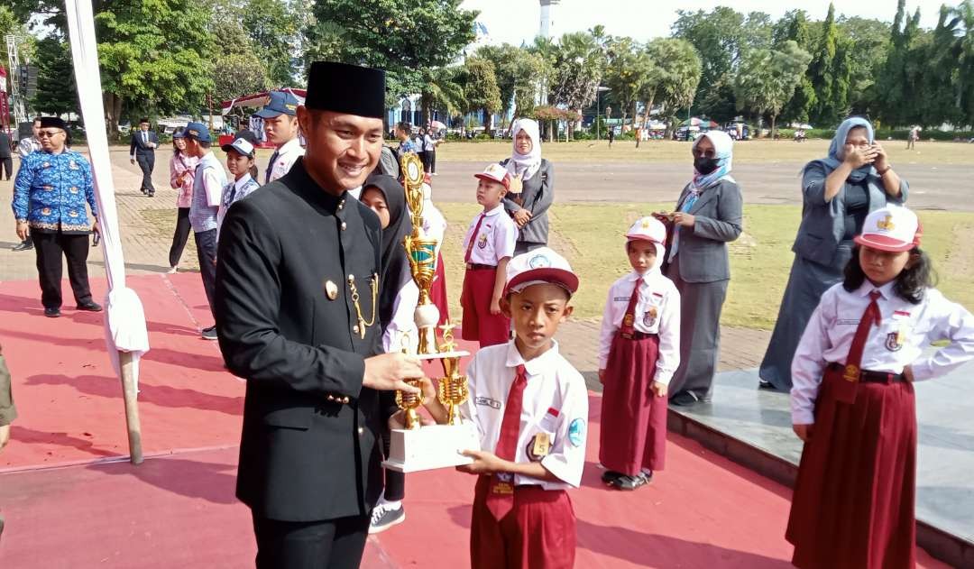 Bupati Tuban menyerahkan piala kepada siswa SD, saat peringatan Hari Pendidikan Nasional (Hardiknas). (Foto: Khoirul Huda/Ngopibareng.id)