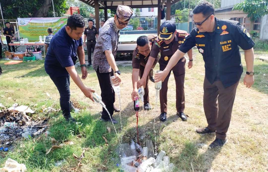 Ratusan botol minuman keras dimusnahkan dengan cara ditumpahkan ke lubang yang sudah disiapkan. (Foto: Istimewa)