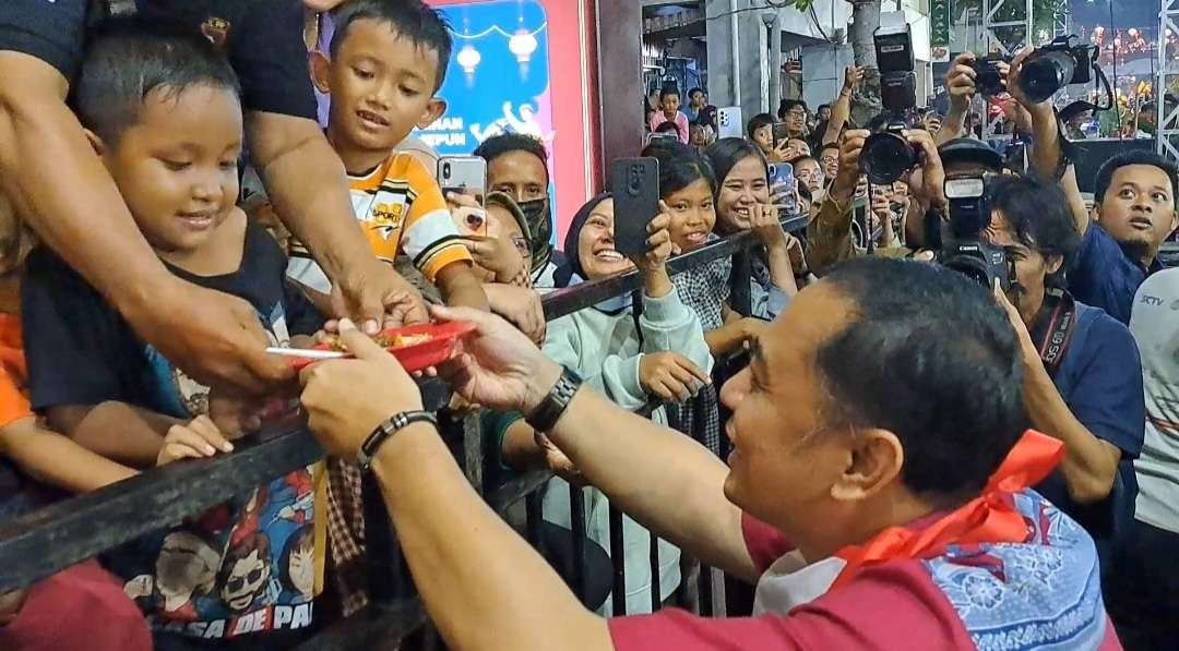 Walikota Surabaya, Eri Cahyadi saat memberikan rujak uleg kepada warga yang ada dibalik pagar besi. (Foto: Pita Sari/Ngopibareng.id)