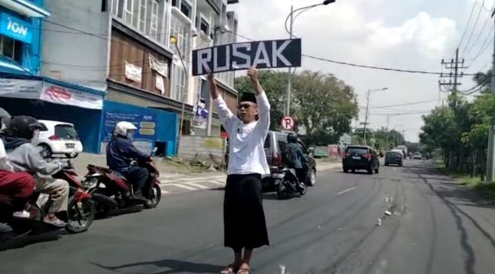 Kusnan Hadi saat melakukan aksinya seorang diri lantaran jalan bergelombang atau rusak. (Foto: Ist)