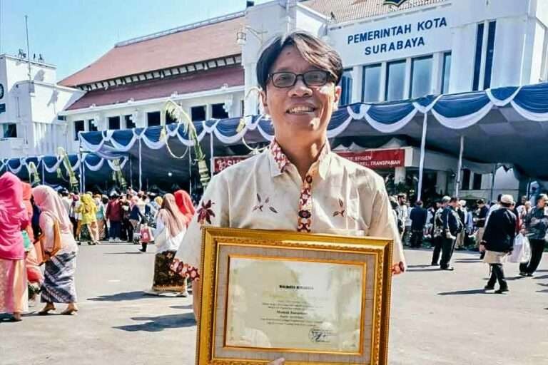 Pengajar dan fotografer Mamuk Ismuntoro, menunjukkan penghargaan khusus dari Wali Kota Surabaya Eri Cahyadi. (Foto: istimewa)