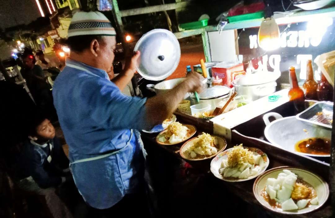 Kang Johari  pedagang Ketoprak asal Cirebon sedang sibuk melayani pembeli. Ia memiliki pelanggan dari berbagai kalangan termasuk selebritis (Foto: Asmanu Sudharso/ngopibareng.id)