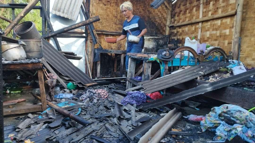 Salah seorang pemilik warung sedang mencari barang yang masih bisa digunakan usai kebakaran. (Foto: Muh Hujaini/Ngopibareng.id)