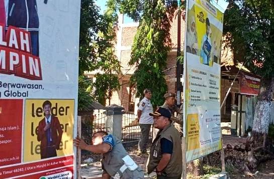 Banner maupun baliho reklame tak berizin dan kadaluwarsa di jalan protokol dicopot paksa anggota Satpol PP Bondowoso.(foto:Satpol PP Damkar Bondowoso)