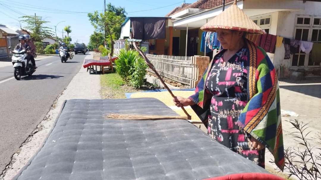 Salah satu warga Desa Kemiren, Kecamatan Glagah, Banyuwangi, Jawa Timur, menjemur kasur dalam ritual Mepe Kasur. (Foto: Muh Hujaini/Ngopibareng.id)