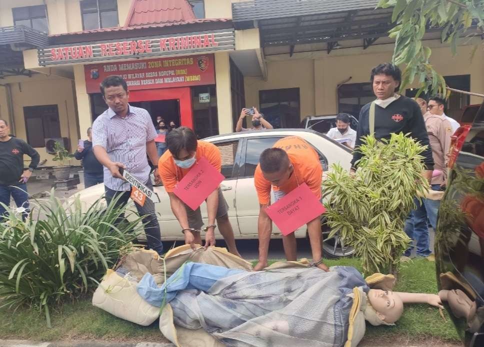 Dayat dan Udin memperagakan membuang mayat korban. (Foto: Dokumentasi Rekonstruksi/Deni Lukmantara/Ngopibareng.id)