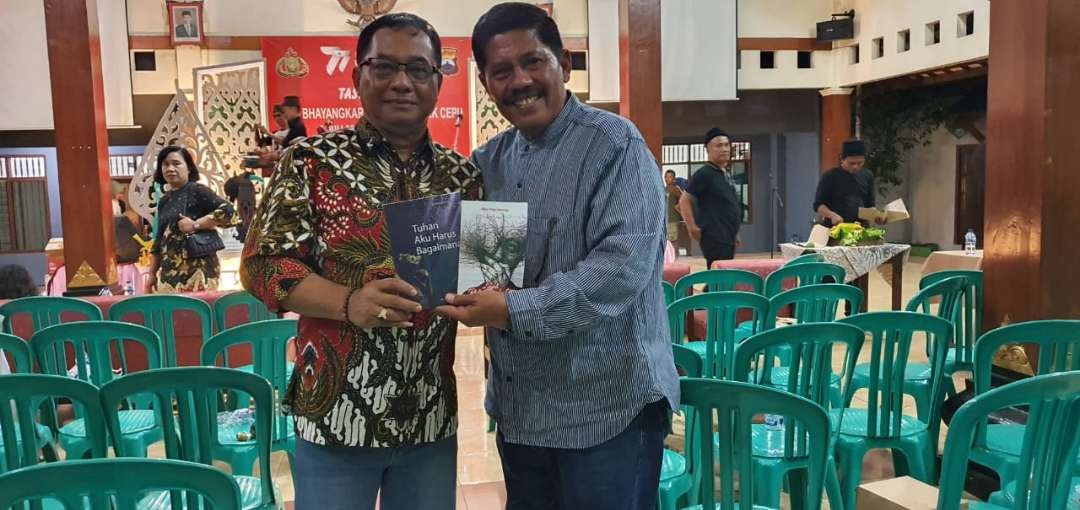 Agus Priyo Hatmoko berkacamata, memberikan buku kapada salah satu penikmat pusi di Cepu (Foto: Ahmad Sampurno/ Ngopibareng.id)