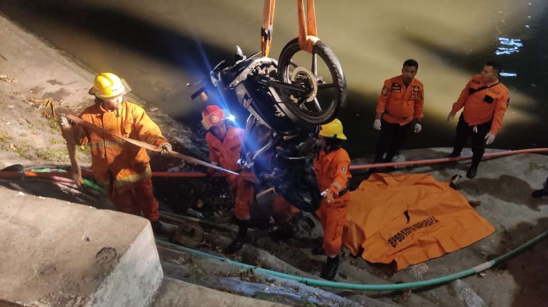 Petugas BPBD Surabaya melakukan evakuasi sepeda motor yang tercebur ke dalam sungai Kalimas, Surabaya, Rabu 5 Juli 2023. (Foto: Fariz Yarbo/Ngopibareng.id)