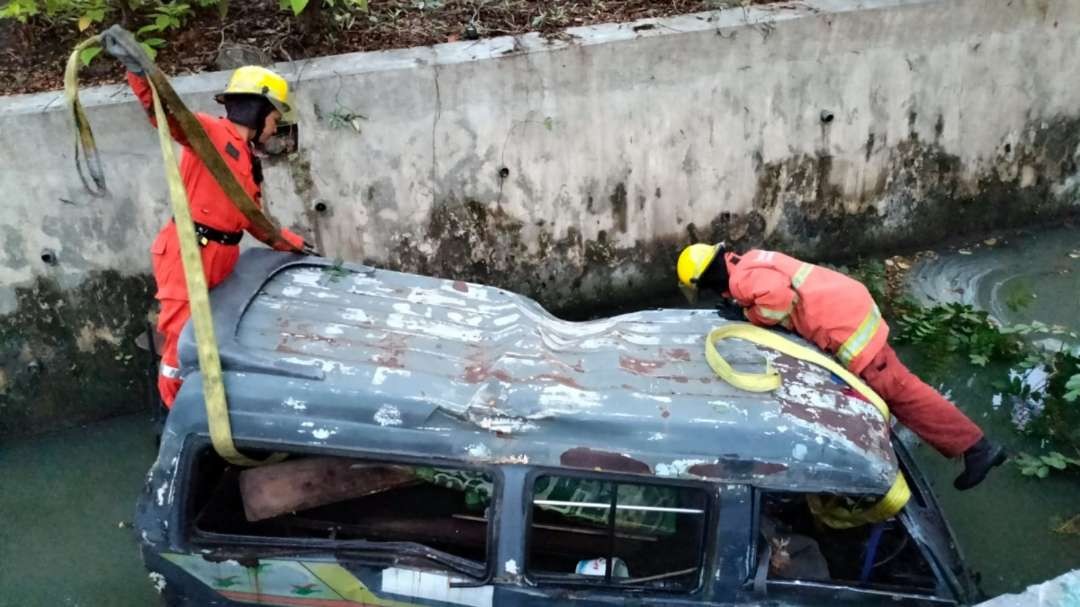 Petugas melakukan evakuasi angkot yang terperosok ke dalam selokan di Jalan A Yani, Surabaya, Kamis 13 Juli 2023. (Foto: Istimewa)