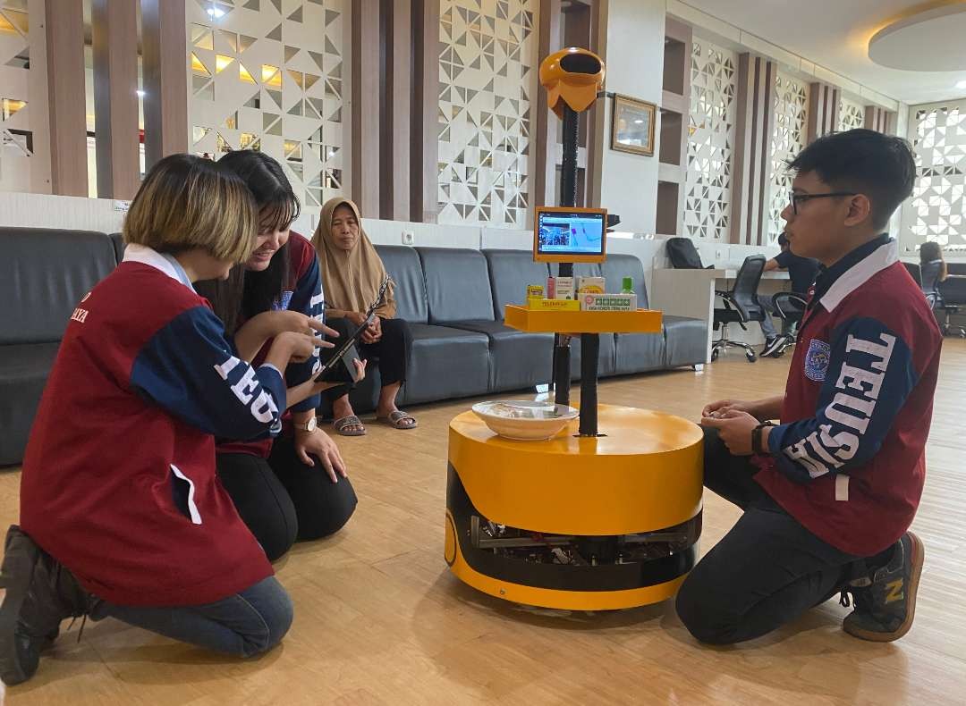 Tiga mahasiswa Ubaya saat mendemokan robot pengantar obat lansia. (Foto: Humas Ubaya)