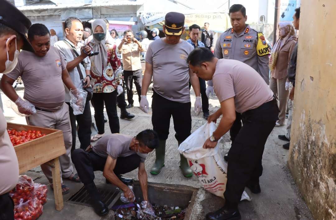 Polisi Situbondo bersihkan sampah menumpuk di selokan Pasar Induk Bondowoso.(Foto:Guido/Ngopibareng.id)