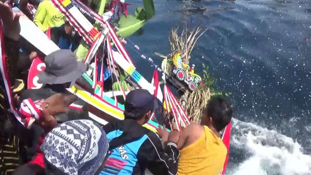 Warga melarung sesaji yang ditempatkan di perahu kecil (foto: istimewa)