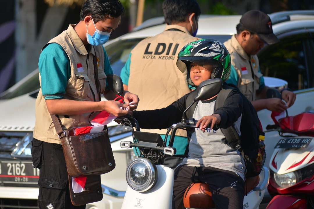 Pemuda LDII Kota Kediri membagikan 1.745 bendera merah putih kepada masyarakat sekitar di Jl Erlangga, Kota Kediri. (Istimewa)