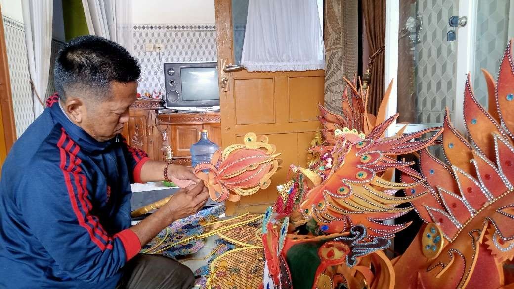 Agus sedang merapikan kostum karnaval buatannya sebelum disewakan ke konsumen (Foto: Khoirul Huda/Ngopibareng.id)