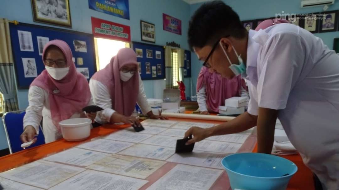 Petugas Dinas Kearsipan dan Perpustakaan (Arpus) Pemerintah Kabupaten Nganjuk tengah memperbaiki dokumen kependudukan masyarakat yang rusak akibat terkena bencana alam. (Foto: dok. nganjukkab)