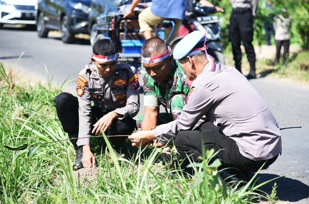 Anggota Polres Bondowoso bersama TNI Kodim 0822 menanam bibit pohon di pinggir jalan desa untuk menghijaukan Bondowoso. (Foto: Guido Saphan/Ngopibareng.id)