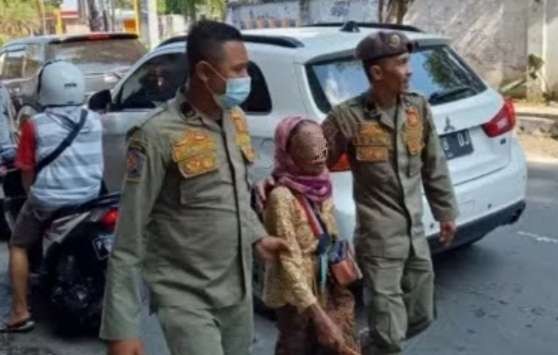 Anggota Satpol PP Damkar Bondowoso menciduk salah seorang perempuan pengemis di jalan raya. (Foto: Satpol PP Damkar Bondowoso)