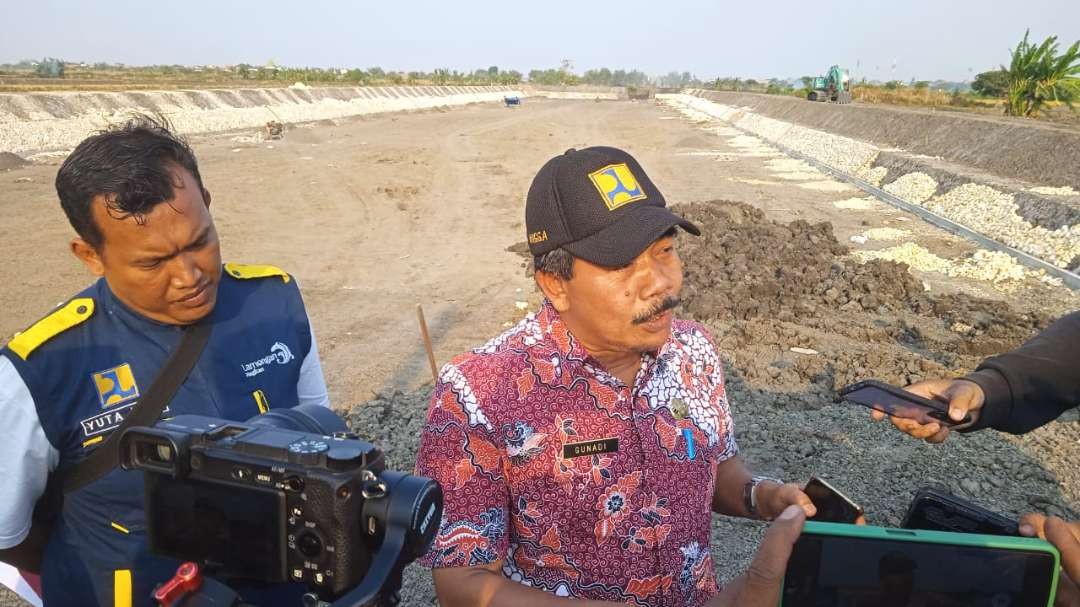 Kepala Dinas PU SDA Lamongan Gunadi dengan latar kolam retensi yang sedang proses pembangunan (Foto :Imron Rosidi/ngooibareng.id)