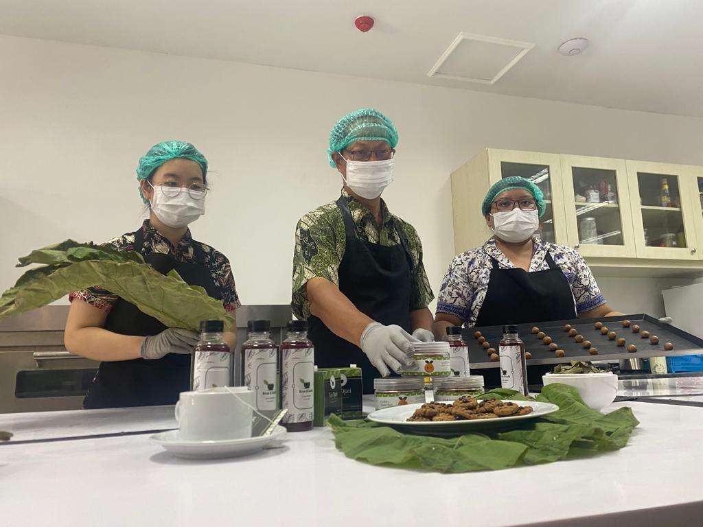 Ketua tim, apt. Tjie Kok, Ph.D (tengah) saat menunjukan produk teh dan kukis dari daun jati. (Foto: dok Ubaya)