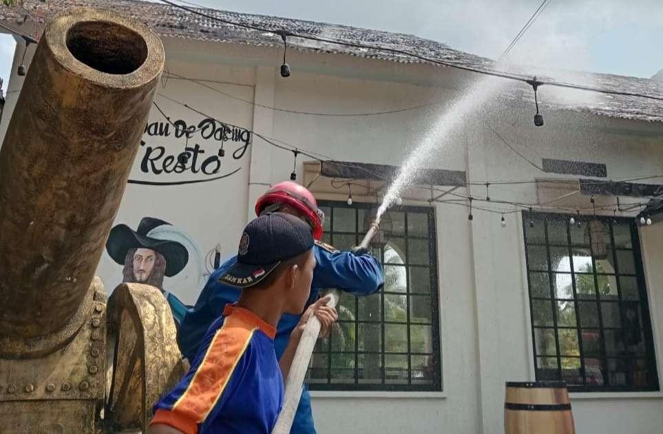 Petugas memadamkan api di atap bangunan. (Foto:istimewa)