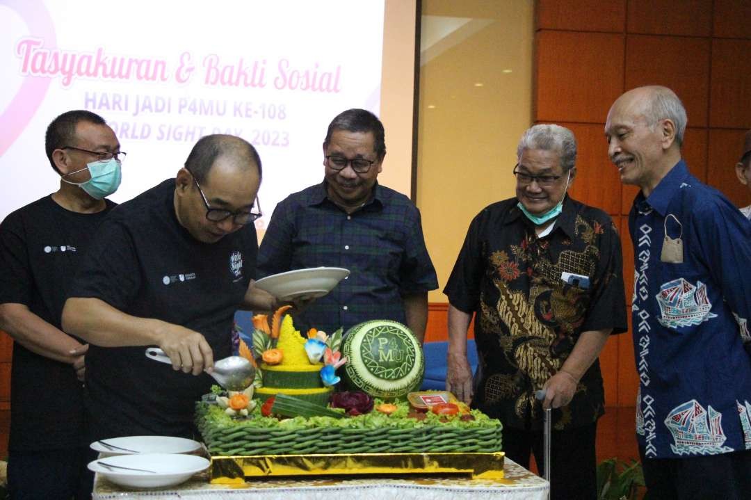 Ketua Badan Pengurus P4MU Arif Afandi saat memotong tumpeng dan memberikannya kepada ketua Dewan Pengawas. (Foto: Pita Sari/Ngopibareng.id)