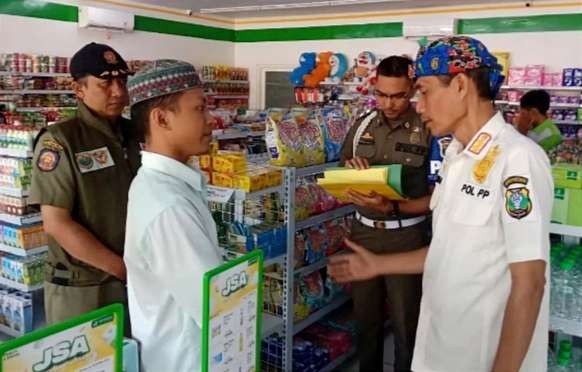 Anggota Satpol PP Bondowoso dipimpin Kabid Gakda Awan Boediyono memperingatkan toko modern berjaringan menaati aturan jam operasional. (Foto: Guido Saphan/Ngopibareng.id)