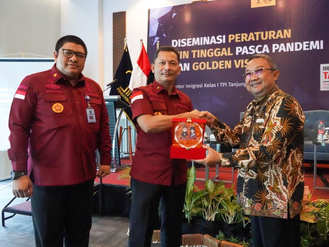 Kadiv Keimigrasian Herdaus (tengah) memberikan cenderamata kepada Koordinator Alih Status Keimigrasian, Tessar Bayu Setyaji disaksikan Kakanim Tanjung Perak, Verico Sandi (kiri). (Foto: Dok Kanwil Kemenkumham Jatim)