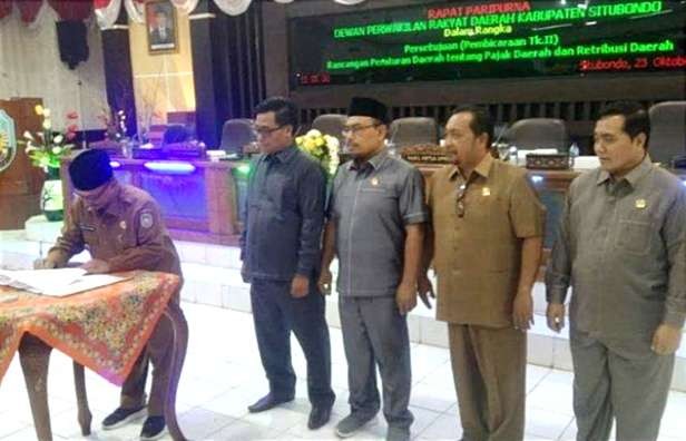 Bupati Situbondo, Karna Suswandi disaksikan pimpinan DPRD menandatangani Perda Pajak dan Retribusi Daerah yang baru disahkan. (Foto: Sekretariat DPRD Situbondo)