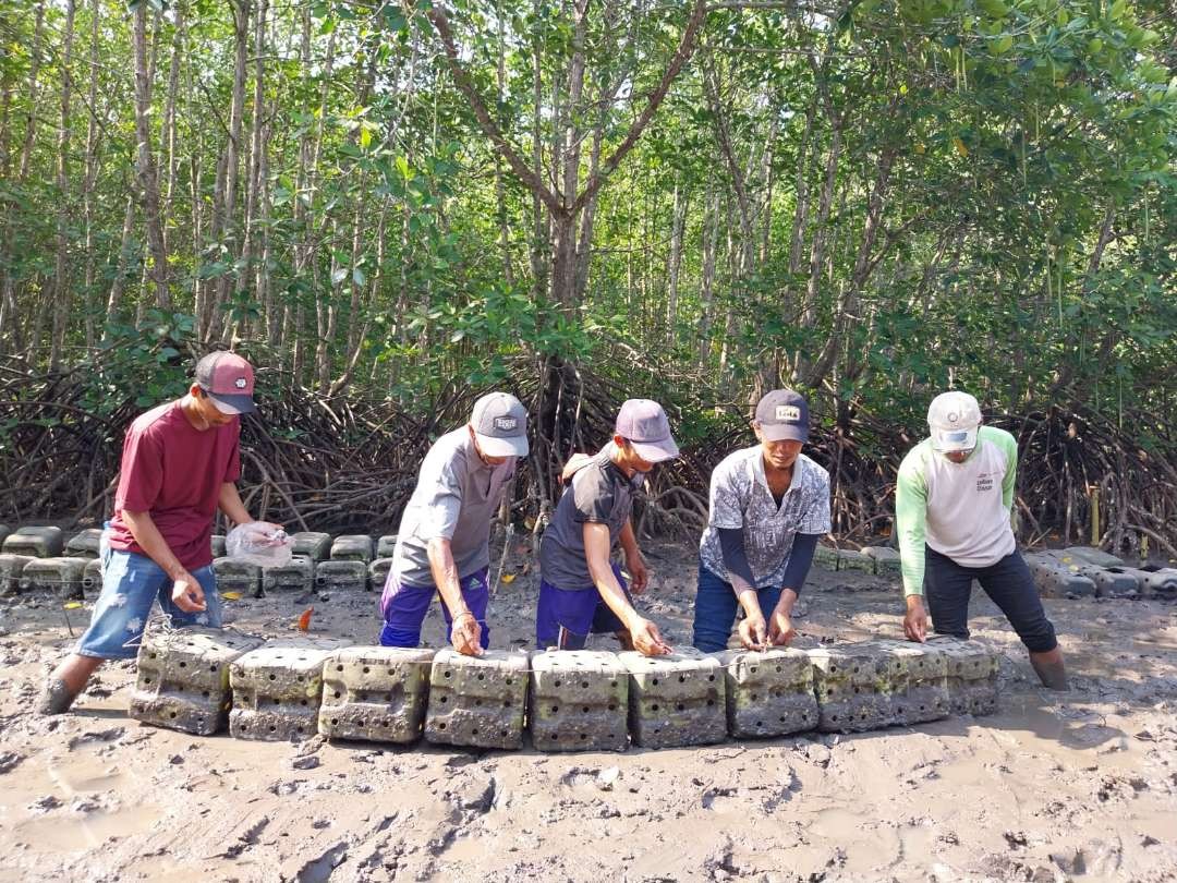 Para nelayan memasukkan benih kepiting ke media pembesaran yang terbuat dari jeriken plastik. (Foto: Istimewa)