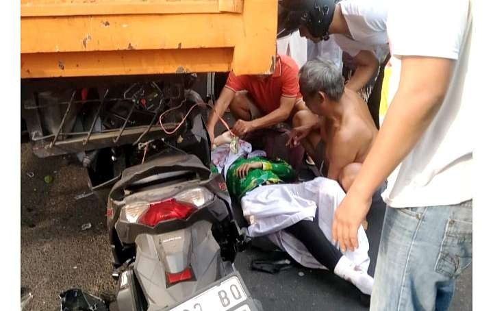 Warga sekitar lokasi kecelakaan memberikan pertolongan siswi SMAN 2 Bondowoso yang meninggal dunia setelah motornya menabrak belakang truk.(Foto: Satlantas Polres Bondowoso)