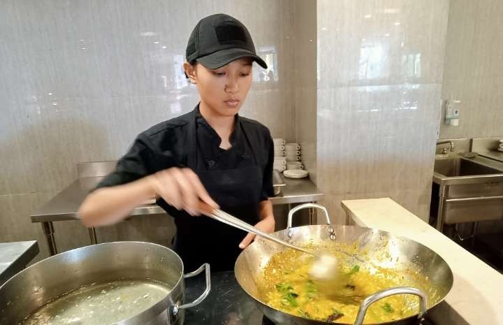 Seorang karyawati sebuah restoran hotel berbintang di Manado sedang menyiapkan bubur Manado (Foto: Asmanu Sudharso/Ngopibareng.id)