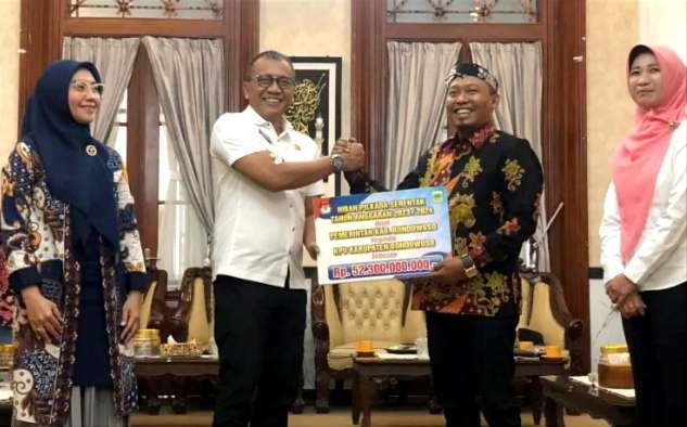 Pj.Bupati Bambang Soekwanto menyerahkan simbolis bantuan dana hibah penyelenggaraan Pilkada Serentak 2024 kepada Ketua KPU setempat Junaedi disaksikan Ketua BawaslubL Nani Agustina dan Pj. Sekda Haeriyaj Yuliati.(Foto:Guido/Ngopibareng.id)