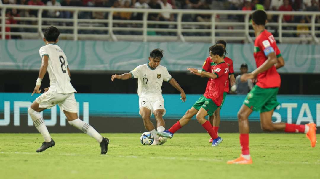 Pemain Timnas U-17, Nabil Asyura (tengah) berduel dengan pemain Maroko dalam laga di Stadion Gelora Bung Tomo, Surabaya, Kamis 16 November 2023. (Foto: LOCWCU17/NFL)