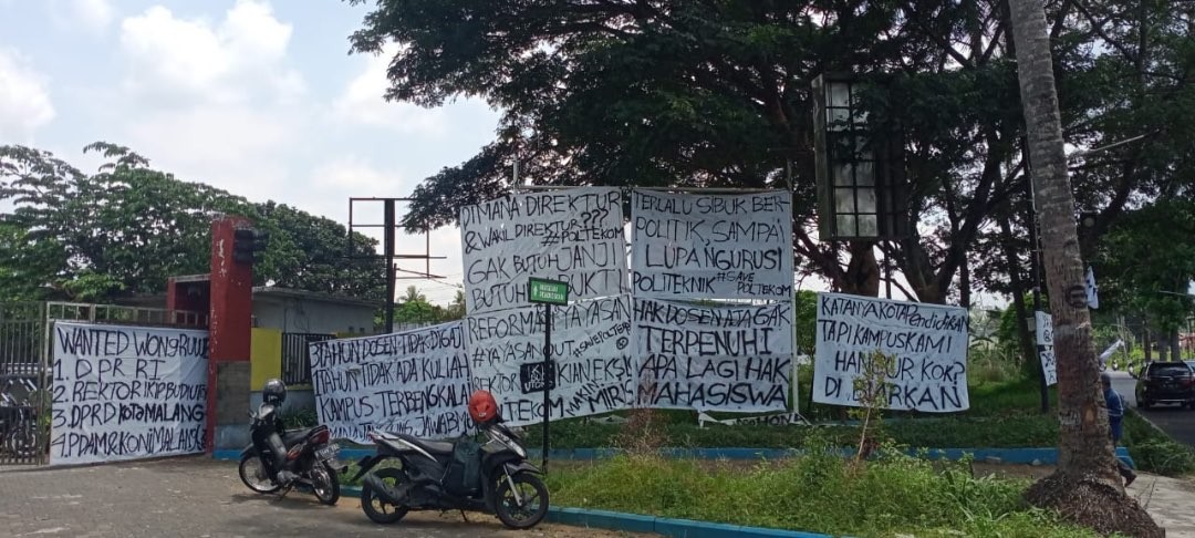 Sejumlah spanduk tuntutan mahasiswa yang terpasang di pintu gerbang Politeknik Kota Malang akibat kegiatan perkuliahan yang terbengkalai (Foto: Lalu Theo/Ngopibareng.id)