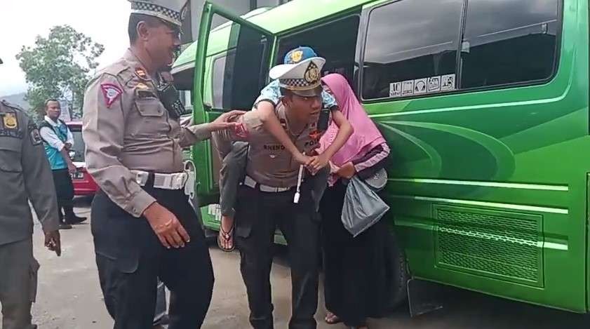 Seorang anggota polisi lalu lintas di Kepolisian Resor Trenggalek menggendong seorang anak penyandang disabilitas di GOR Gajah Putih, Trenggalek pada Minggu 3 Desember 2023.(Foto: dok. polres)