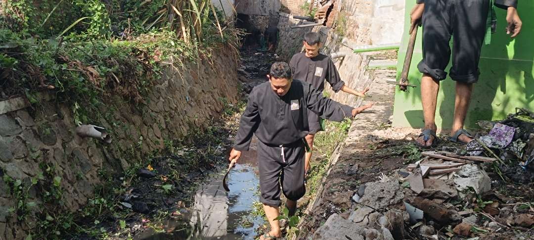 Peduli lingkungan, pendekar PSHT Kediri gotong royong membersihkan aliran sungai. (Foto: Fendi Lesmana/Ngopibareng.id)